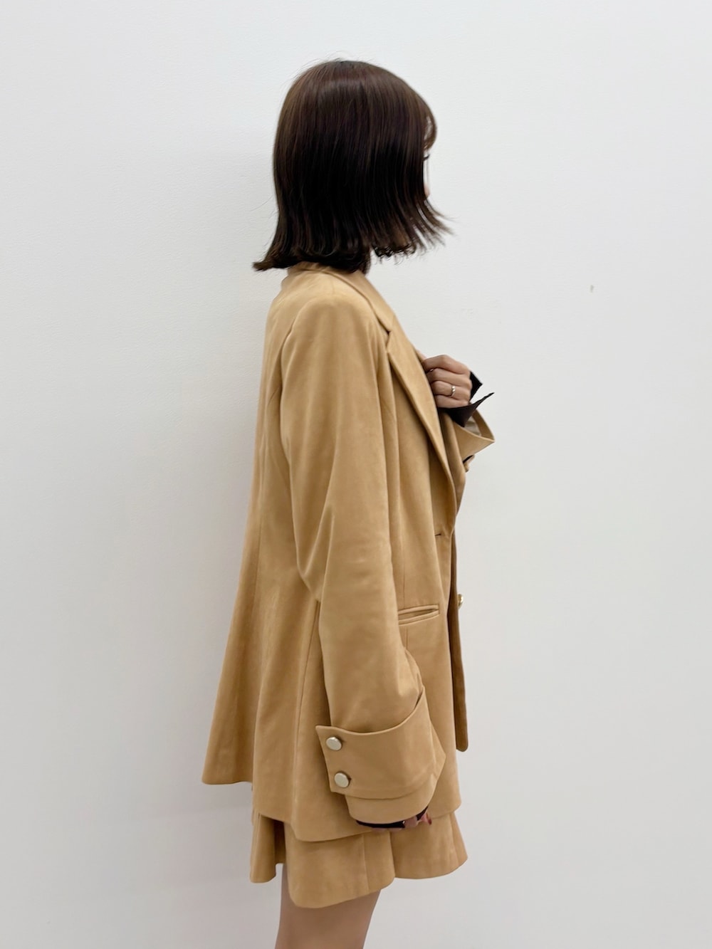 ブラウン系のニット/セーター、ブラウン系のスカート、ブラウン系のテーラードジャケットを着用したレディースの秋コーディネートの2枚目の写真