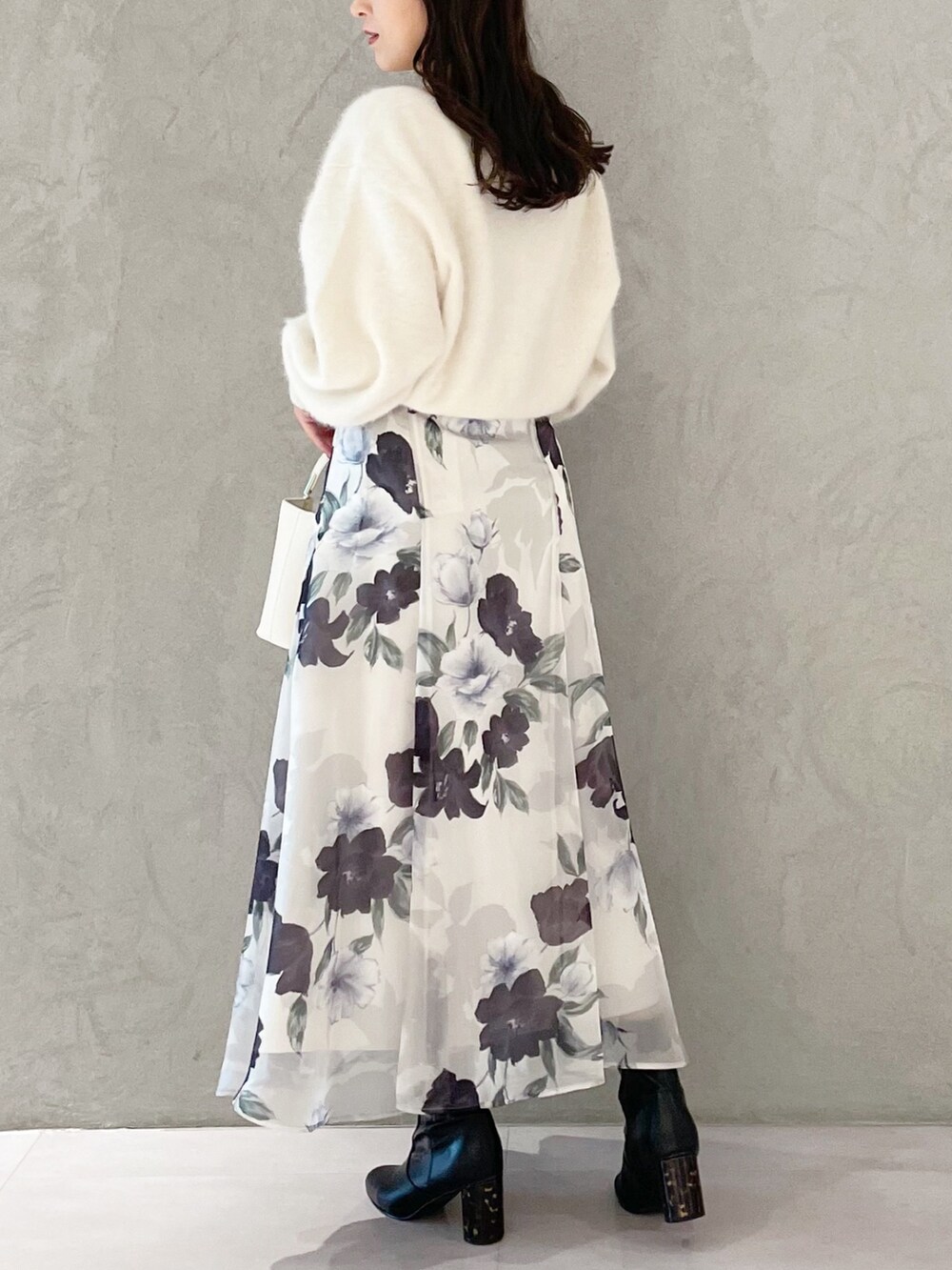 ホワイト系のハンドバッグ、ブラック系のブーツ、ブルー系のスカートを着用したレディースの秋コーディネートの3枚目の写真