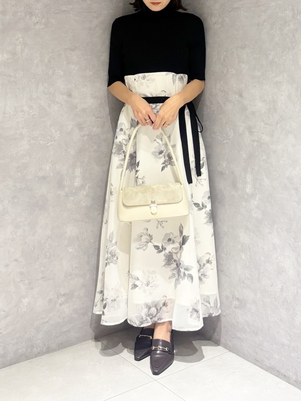 ブラック系のワンピース、ブラウン系のパンプス、ホワイト系のハンドバッグを着用したレディースの春コーディネートの6枚目の写真