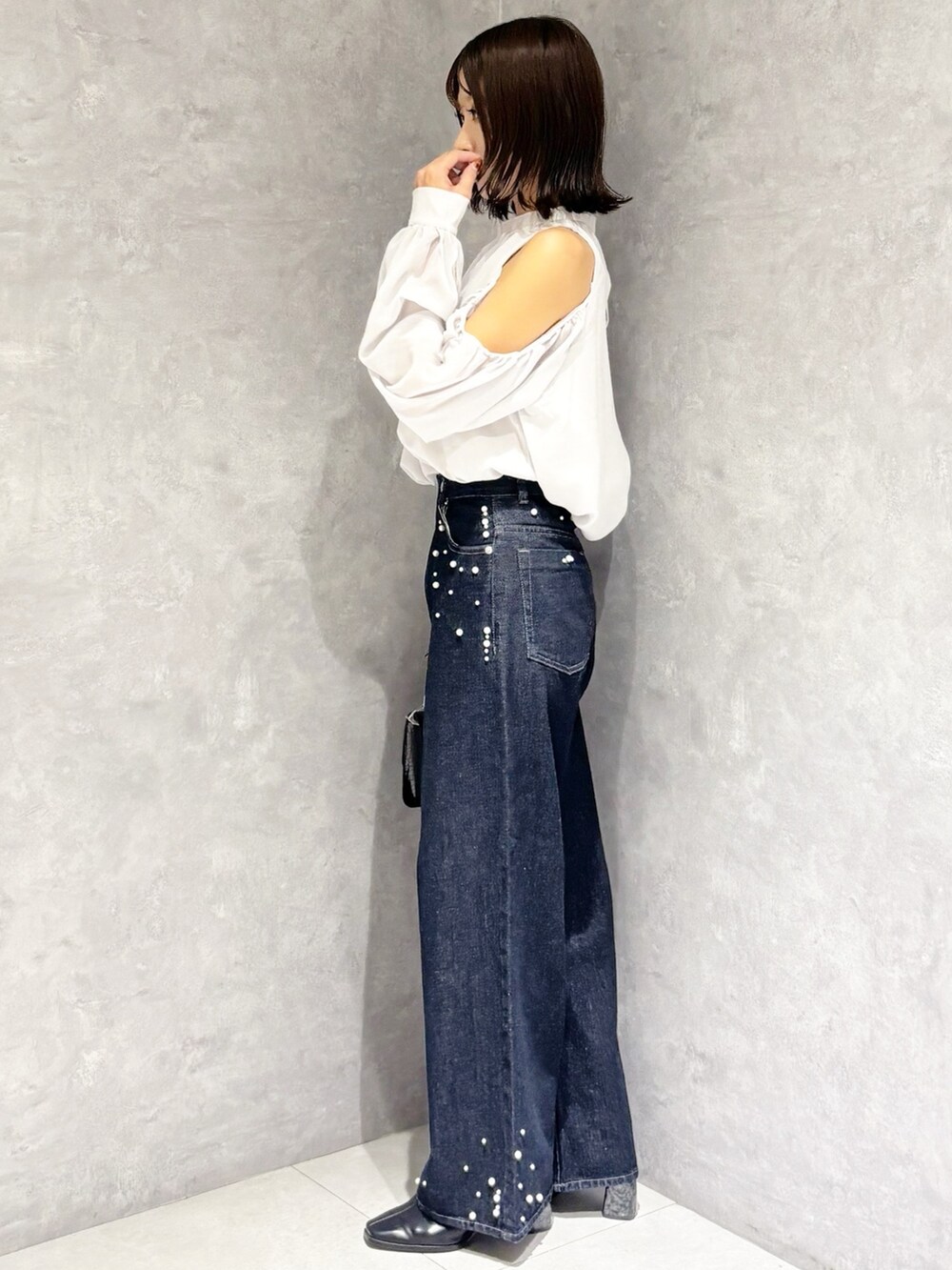 ブルー系のデニムパンツ、ブラック系のブーツ、ブラック系のハンドバッグを着用したレディースの秋コーディネートの4枚目の写真