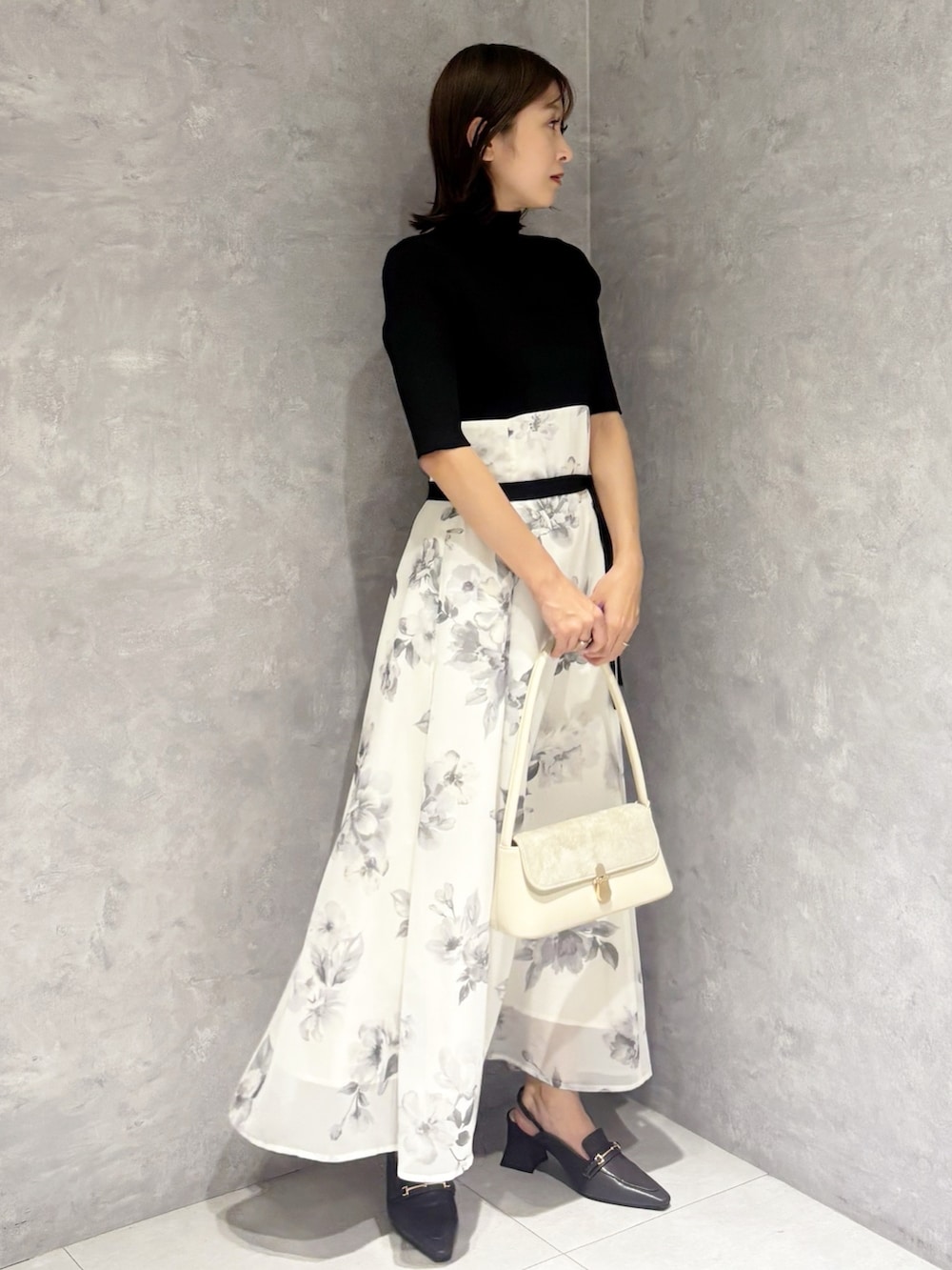 ブラック系のワンピース、ブラウン系のパンプス、ホワイト系のハンドバッグを着用したレディースの春コーディネートの5枚目の写真