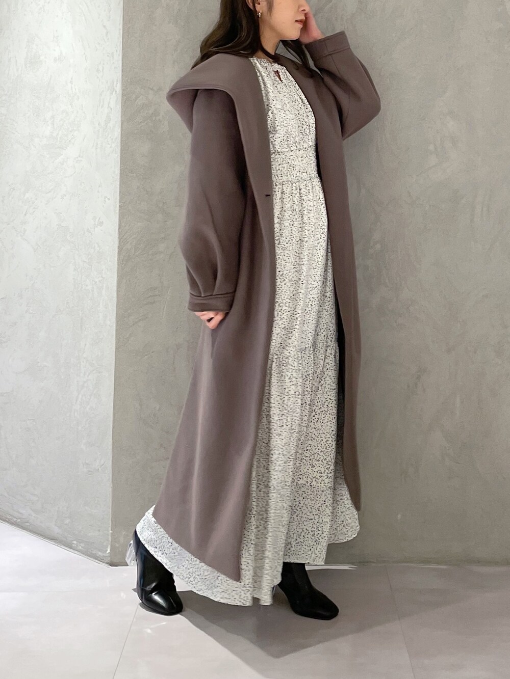 ホワイト系のワンピース、ブラウン系のチェスターコート、ブラック系のブーツを着用したレディースの秋コーディネートの2枚目の写真