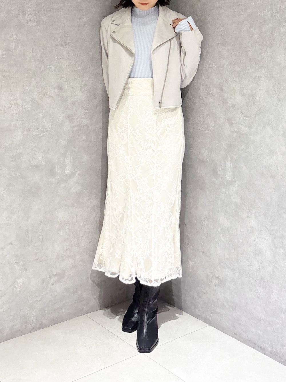 ホワイト系のスカート、ブルー系のニット/セーター、ベージュ系のライダースジャケットを着用したレディースの冬コーディネートの5枚目の写真