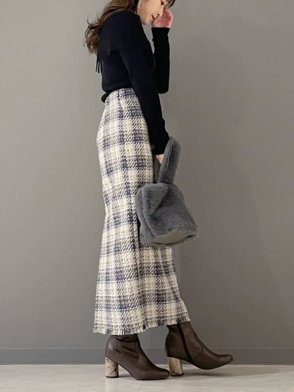 グリーン系のハンドバッグ、ブラック系のニット/セーター、ブルー系のスカートを着用したレディースの冬コーディネートの4枚目の写真