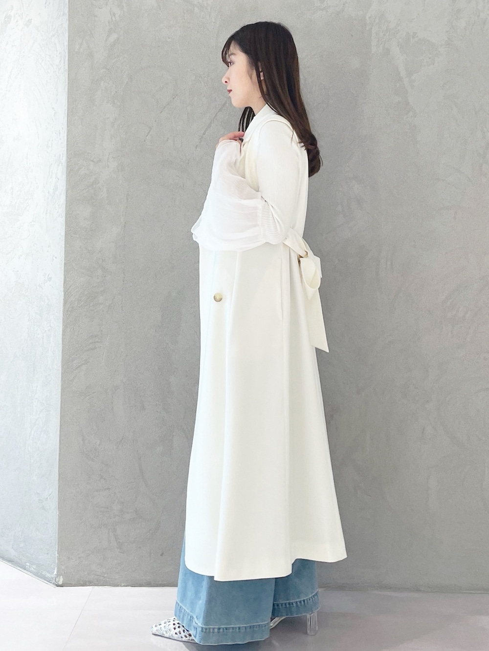 ブルー系のデニムパンツ、ホワイト系のショルダーバッグ、ホワイト系のニット/セーターを着用したレディースの冬コーディネートの2枚目の写真