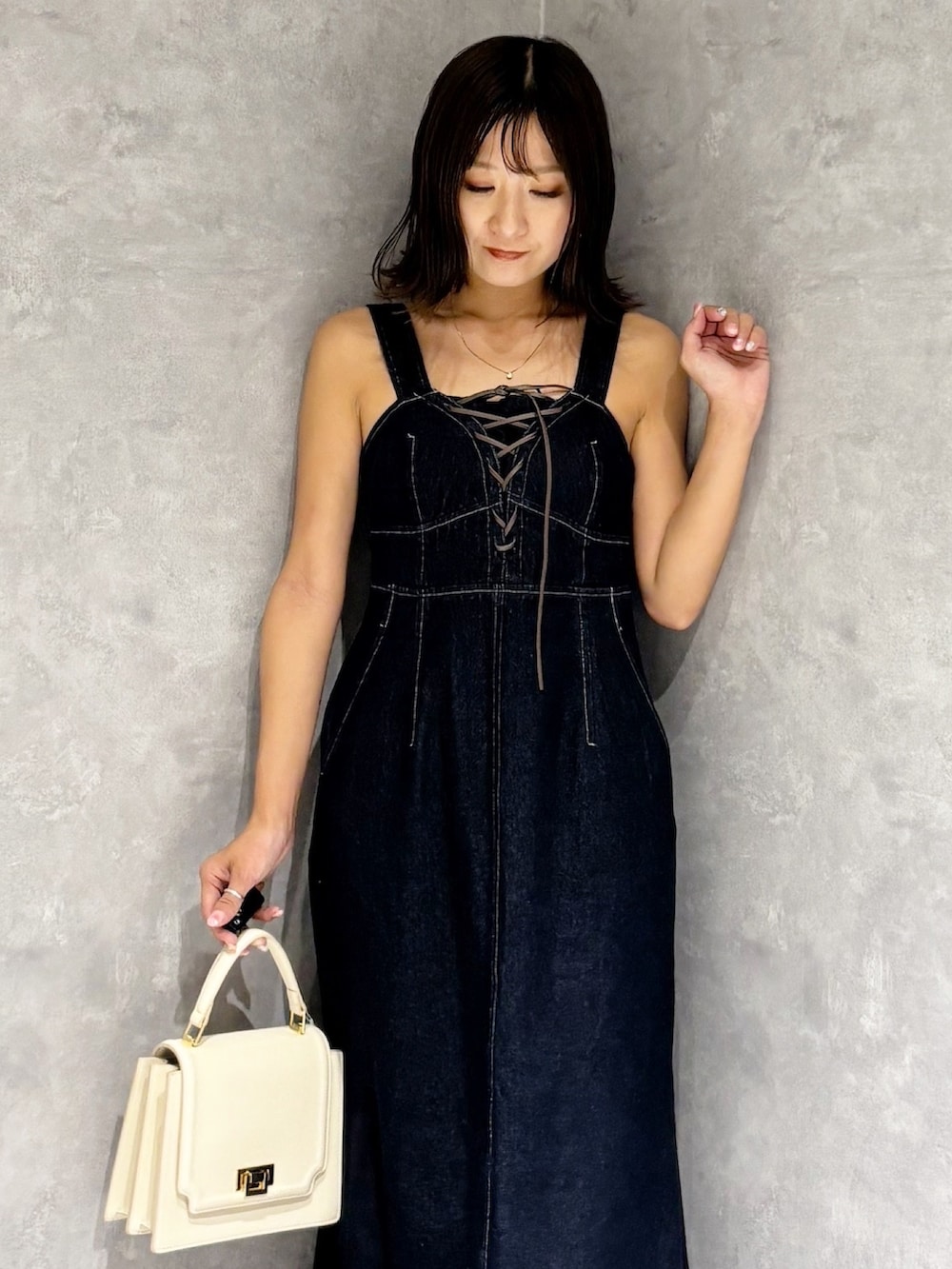 ブルー系のワンピース、ブラウン系のブーツ、ホワイト系のハンドバッグを着用したレディースの夏コーディネートの7枚目の写真
