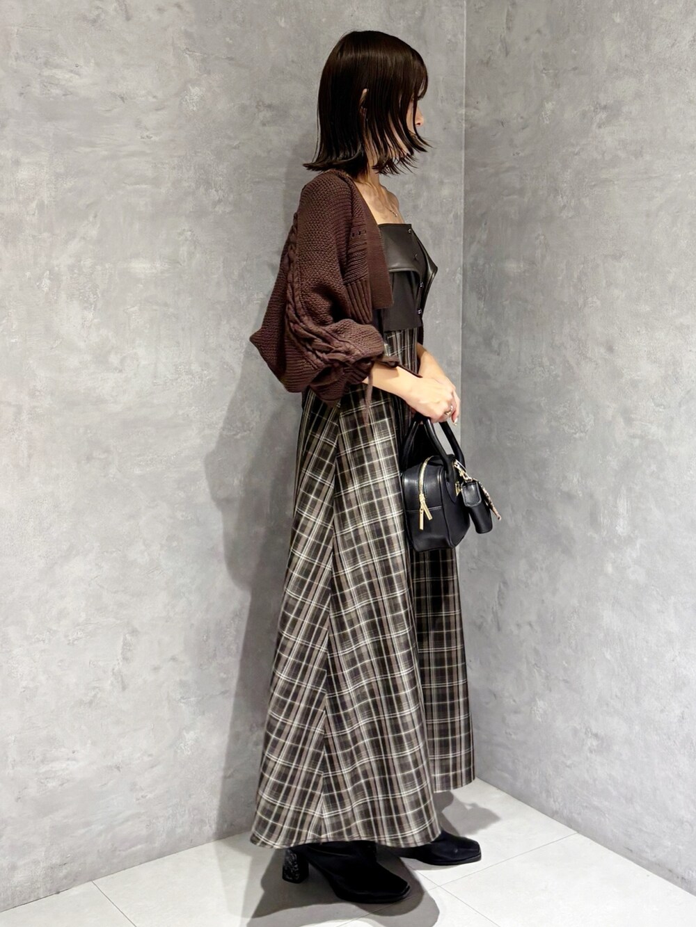 ブラウン系のワンピース、ブラック系のブーツ、ブラック系のハンドバッグを着用したレディースの秋コーディネートの2枚目の写真