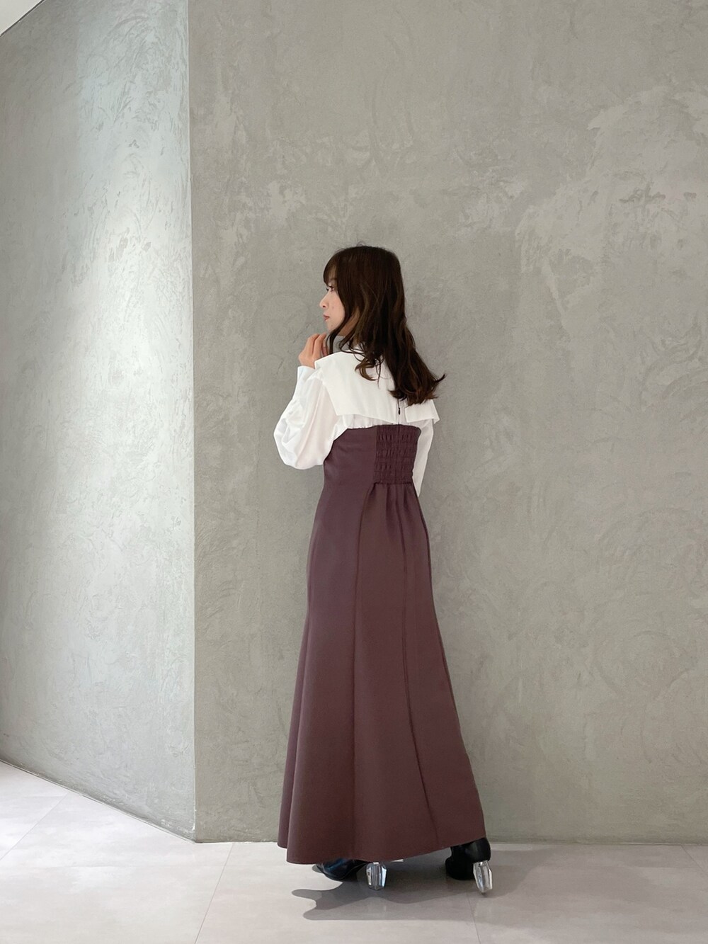 パープル系のワンピース、ブラック系のブーツ、ホワイト系のトレンチコートを着用したレディースの冬コーディネートの4枚目の写真