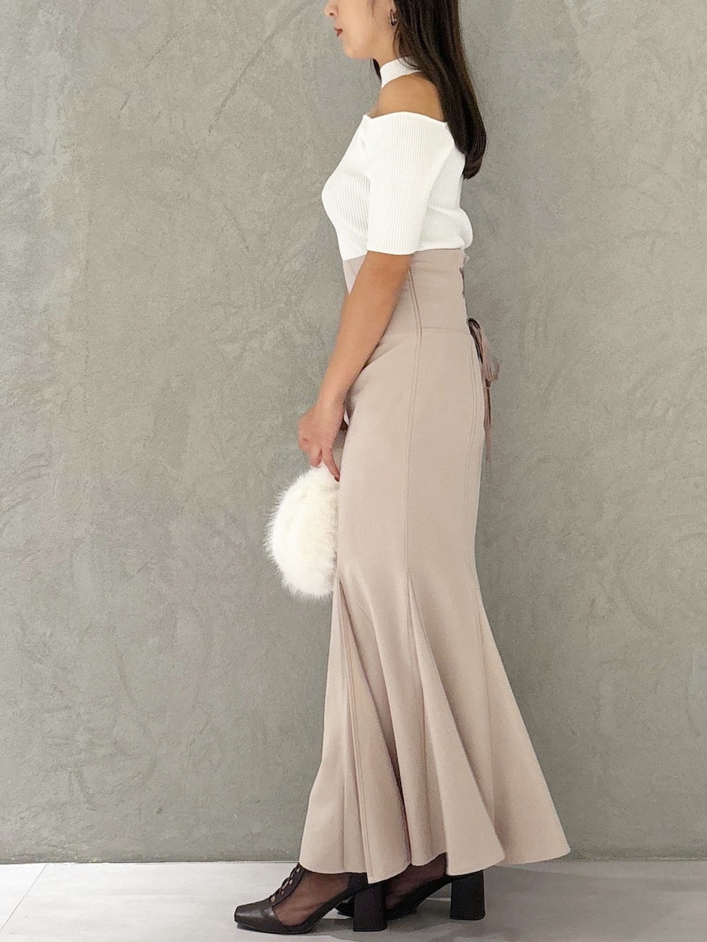 ピンク系のスカート、ブラウン系のブーツ、ホワイト系のハンドバッグを着用したレディースの秋コーディネートの2枚目の写真