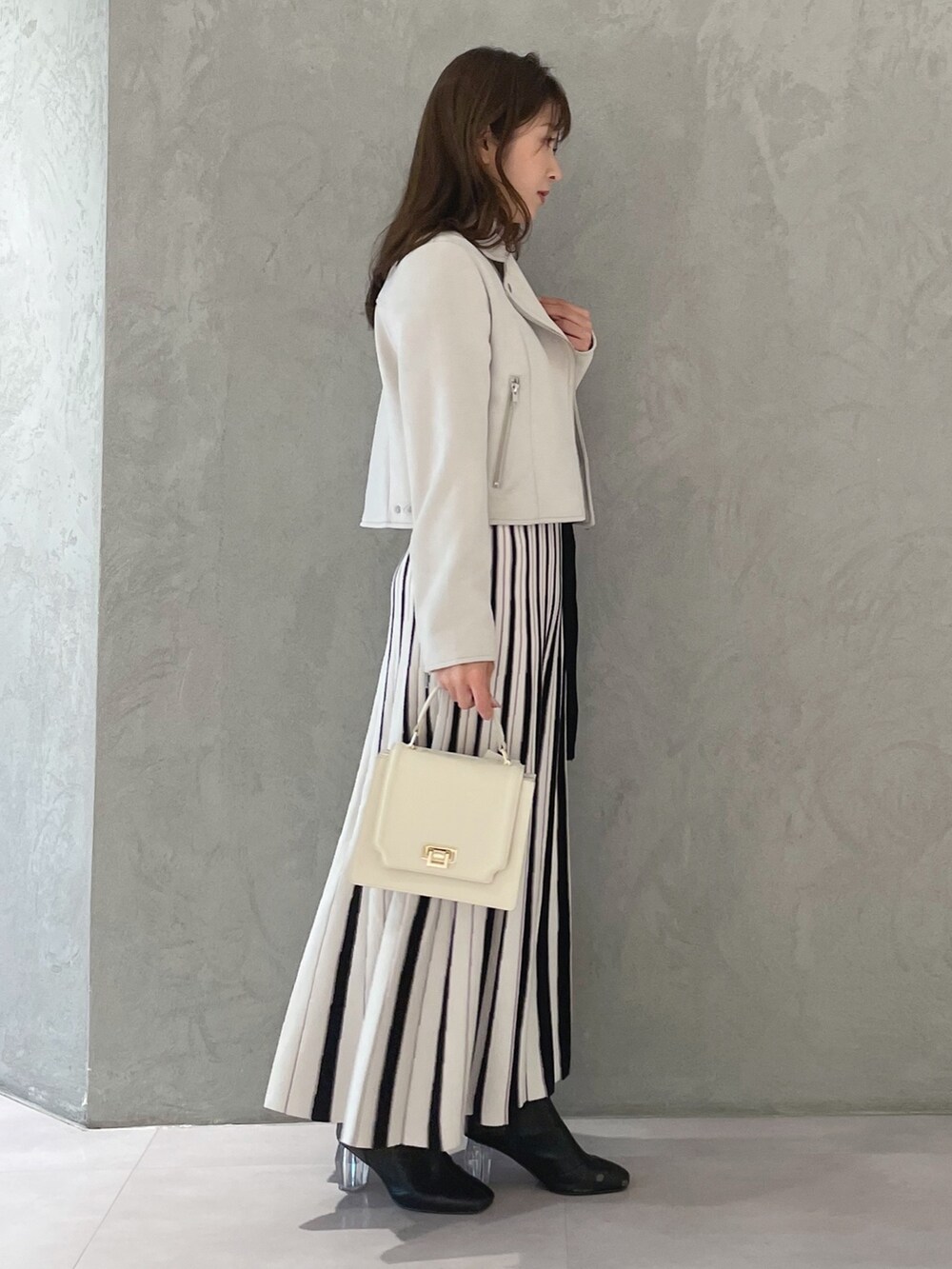 ホワイト系のワンピース、ピンク系のライダースジャケット、ホワイト系のハンドバッグを着用したレディースの春コーディネートの2枚目の写真