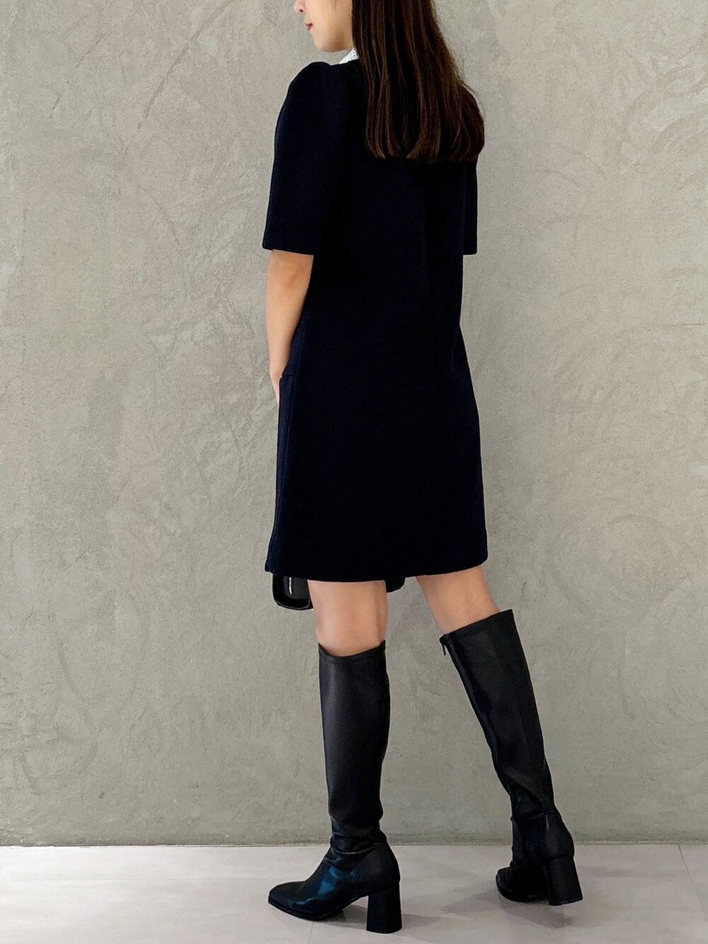 ブルー系のワンピース、ブラック系のブーツ、ブラック系のショルダーバッグを着用したレディースの秋コーディネートの2枚目の写真