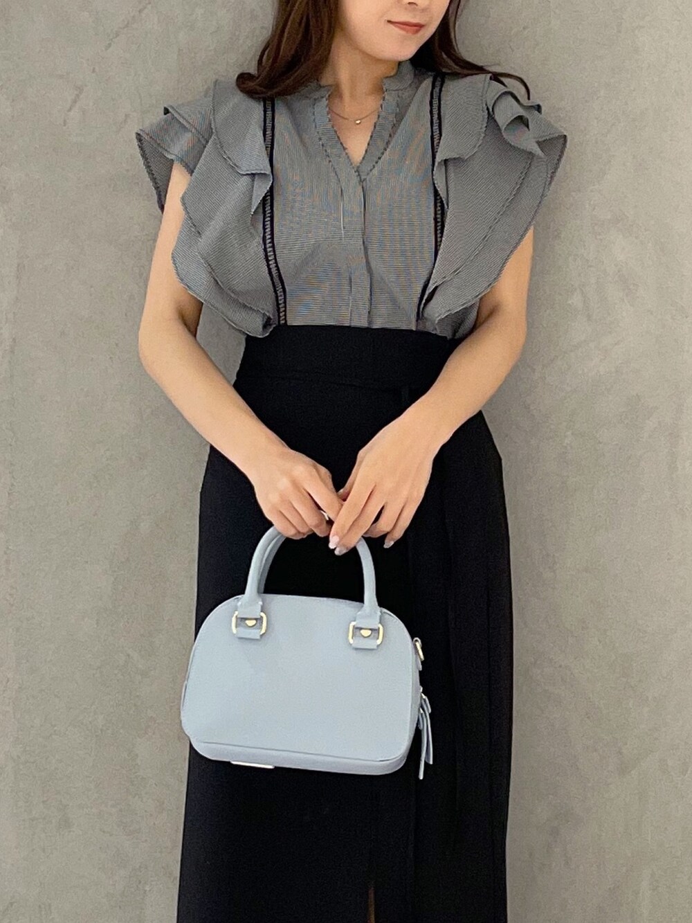 ブラック系のスカート、ブラック系のサンダル、ブルー系のボストンバッグを着用したレディースの春コーディネートの3枚目の写真