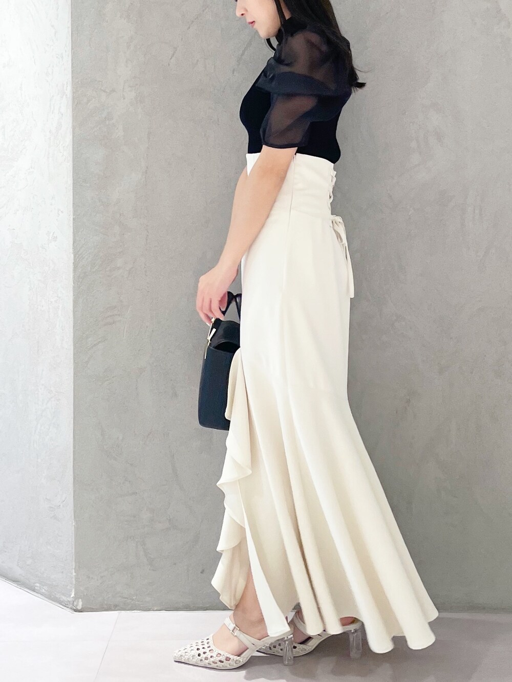 ホワイト系のパンプス、ブラック系のハンドバッグ、ブラック系のニット/セーターを着用したレディースの春コーディネートの3枚目の写真