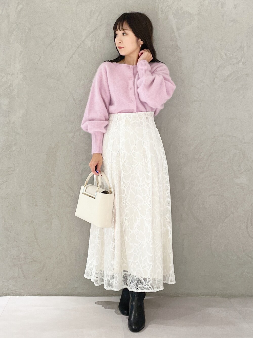 ホワイト系のハンドバッグ、ブラック系のブーツ、ホワイト系のスカートを着用したレディースの秋コーディネートの5枚目の写真