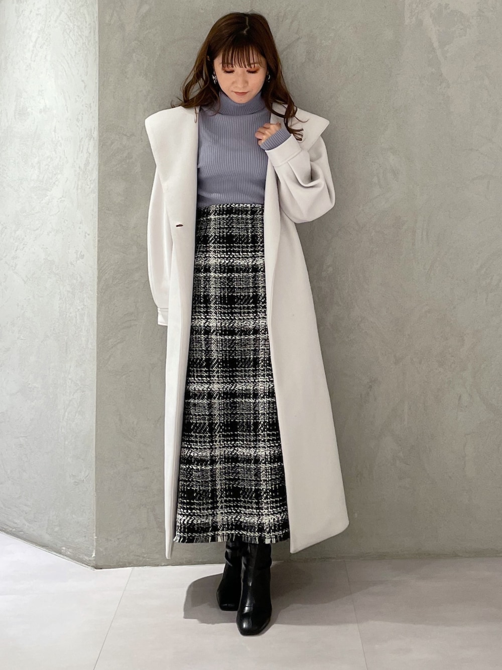 ブルー系のニット/セーター、ブラック系のスカート、ホワイト系のチェスターコートを着用したレディースの冬コーディネートの6枚目の写真