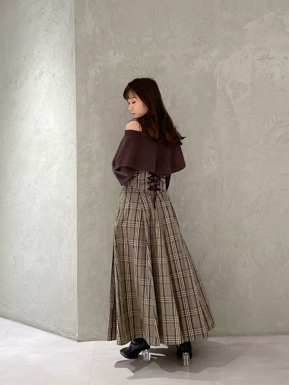 ベージュ系のスカート、ブラウン系のニット/セーター、ブラック系のブーツを着用したレディースの秋コーディネートの5枚目の写真