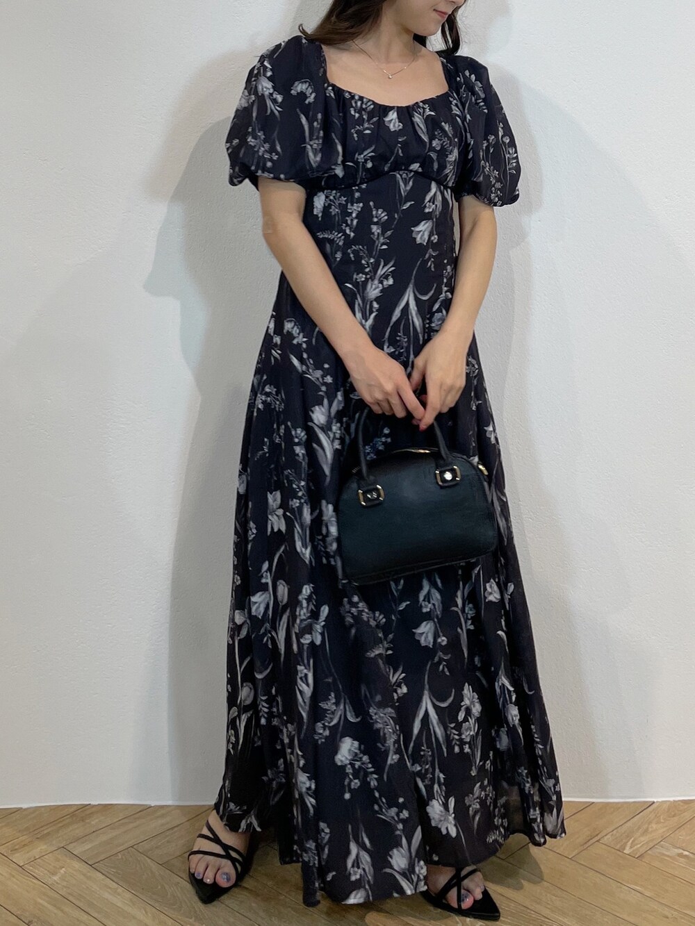 ブラック系のハンドバッグ、ブラック系のサンダル、グレー系のワンピースを着用したレディースの春コーディネートの4枚目の写真