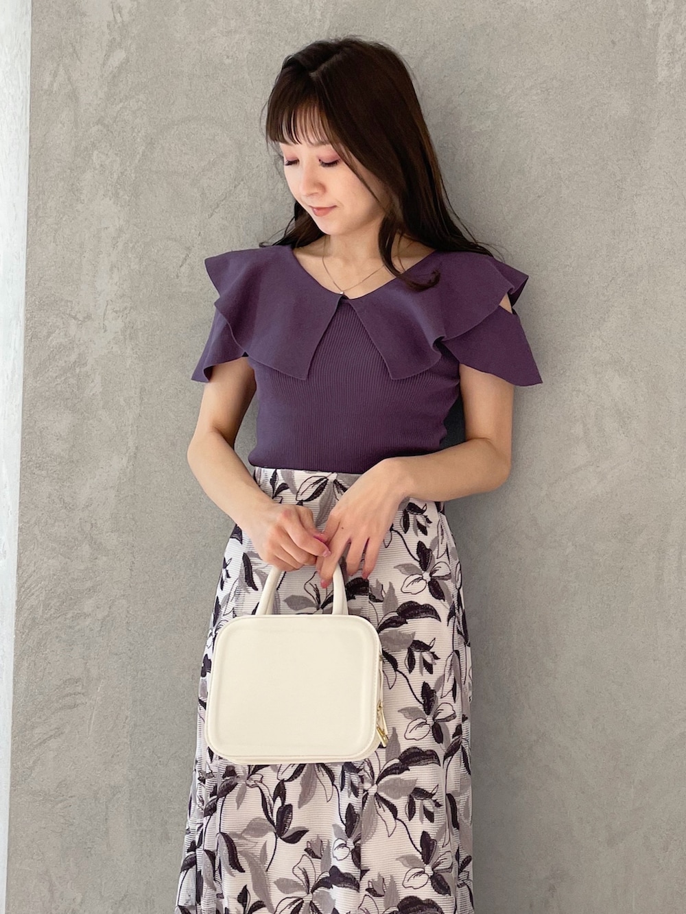 ホワイト系のハンドバッグ、ブラック系のサンダル、パープル系のニット/セーターを着用したレディースの春コーディネートの3枚目の写真