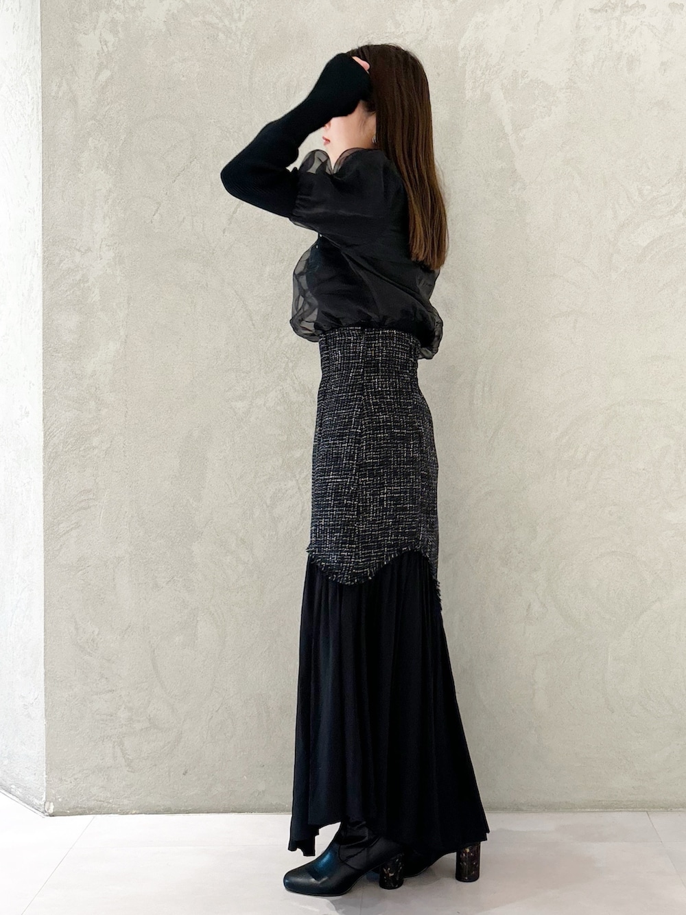 ブラック系のスカート、ブラック系のショルダーバッグ、ブラック系のブーツを着用したレディースの秋コーディネートの6枚目の写真