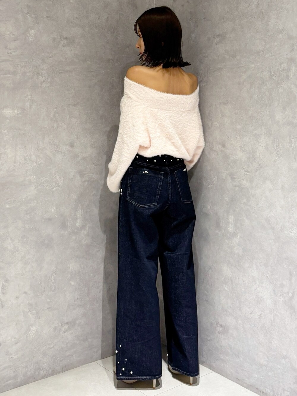 ブルー系のデニムパンツ、シルバー系のパンプス、ピンク系のニット/セーターを着用したレディースの秋コーディネートの4枚目の写真