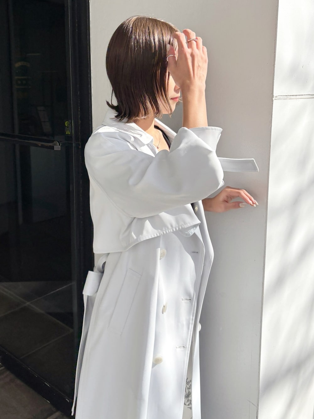 ブラック系のワンピース、ブラウン系のパンプス、ブルー系のトレンチコートを着用したレディースの春コーディネートの4枚目の写真