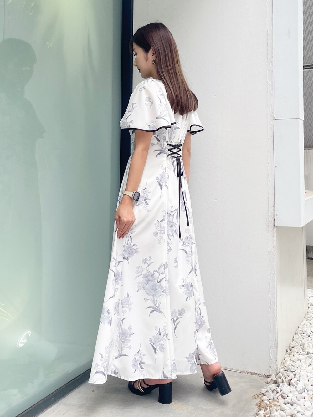 ブラック系のサンダル、ホワイト系のワンピースを着用したレディースの夏コーディネートの2枚目の写真