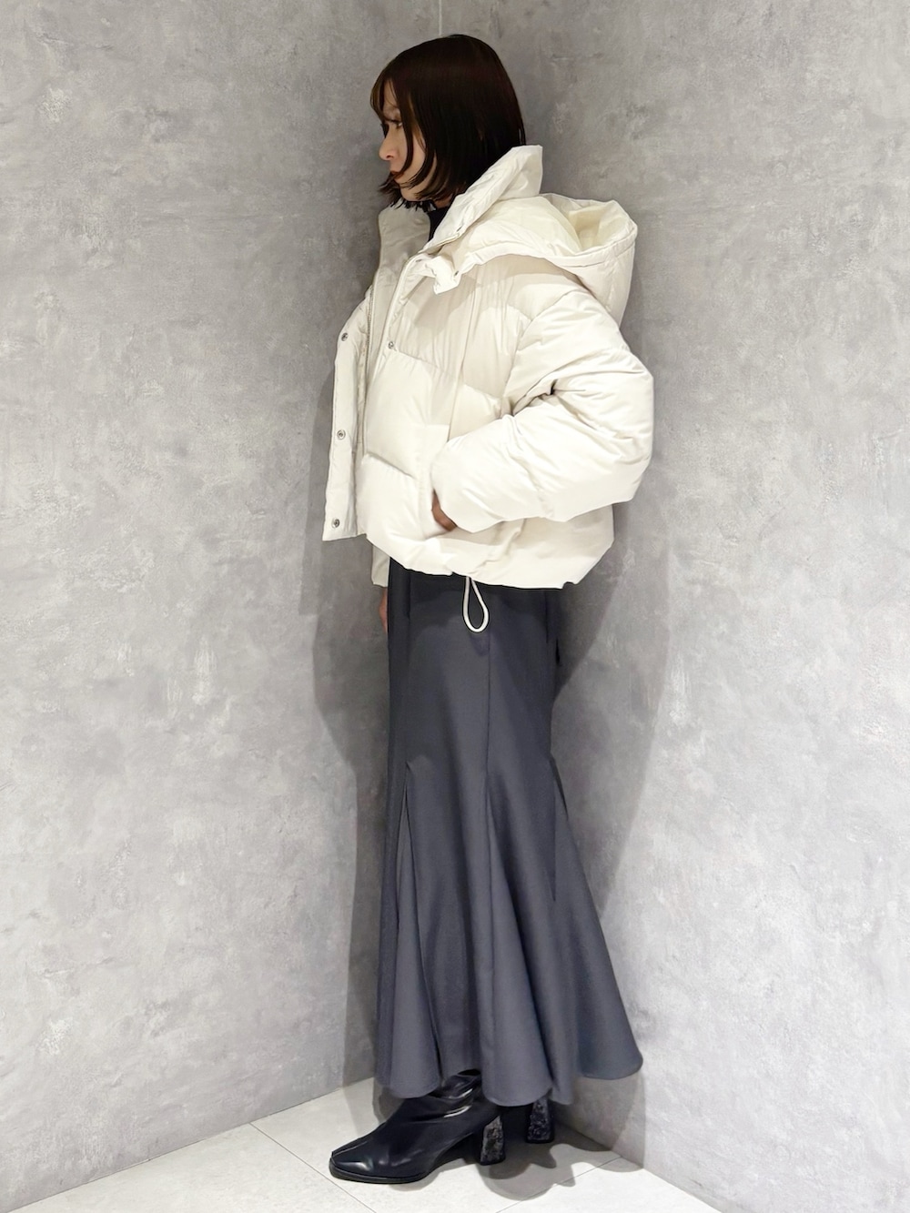 グレー系のスカート、グレー系のニット/セーター、ホワイト系のダウンジャケット/コートを着用したレディースの冬コーディネートの3枚目の写真