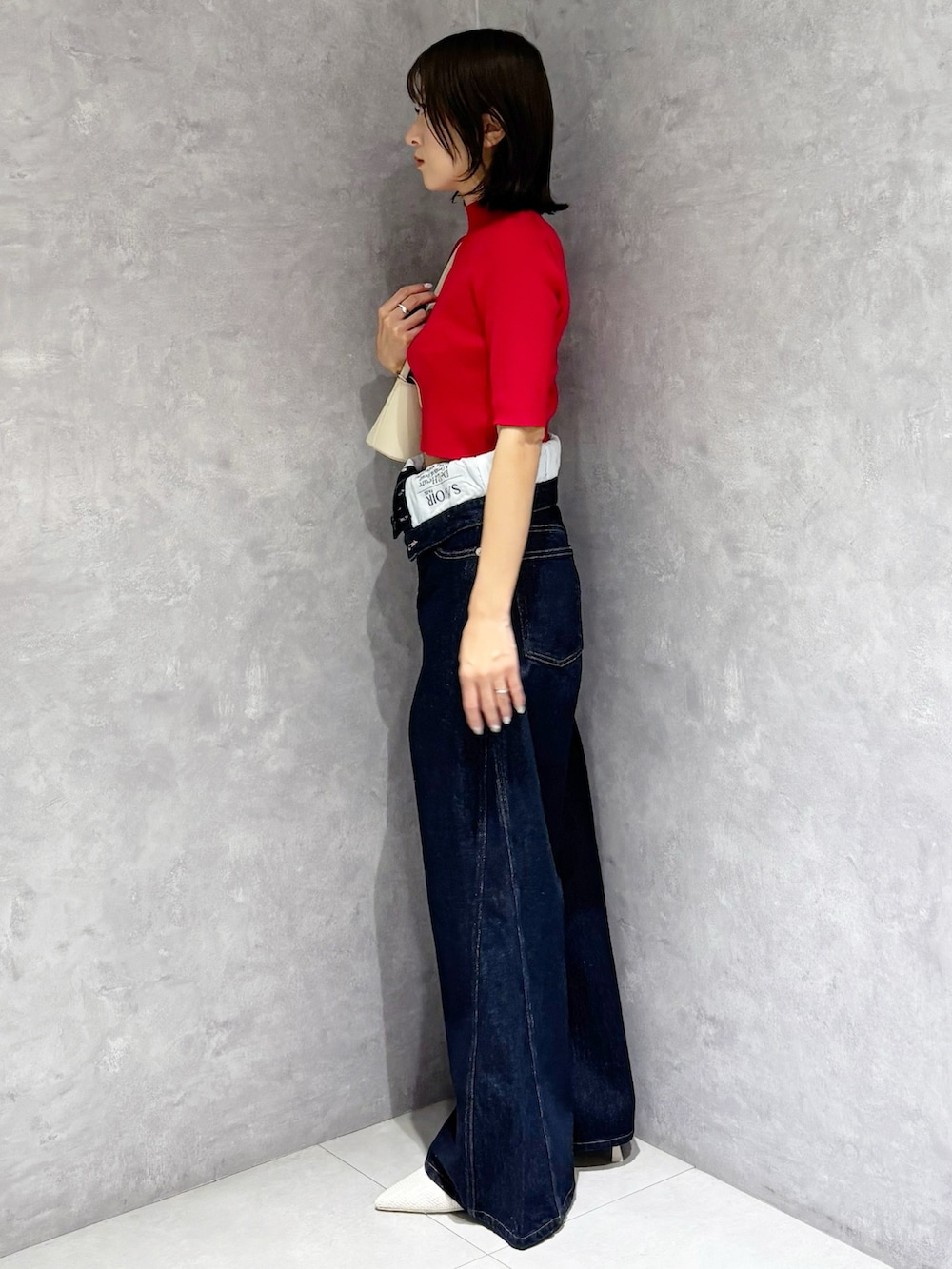 ブルー系のその他パンツ、レッド系のニット/セーター、ホワイト系のハンドバッグを着用したレディースの春コーディネートの4枚目の写真