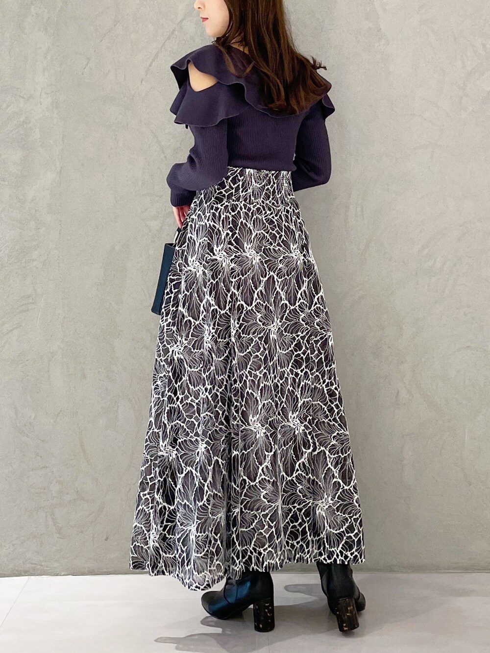 グレー系のスカート、ブラック系のブーツ、ブラック系のハンドバッグを着用したレディースの冬コーディネートの4枚目の写真