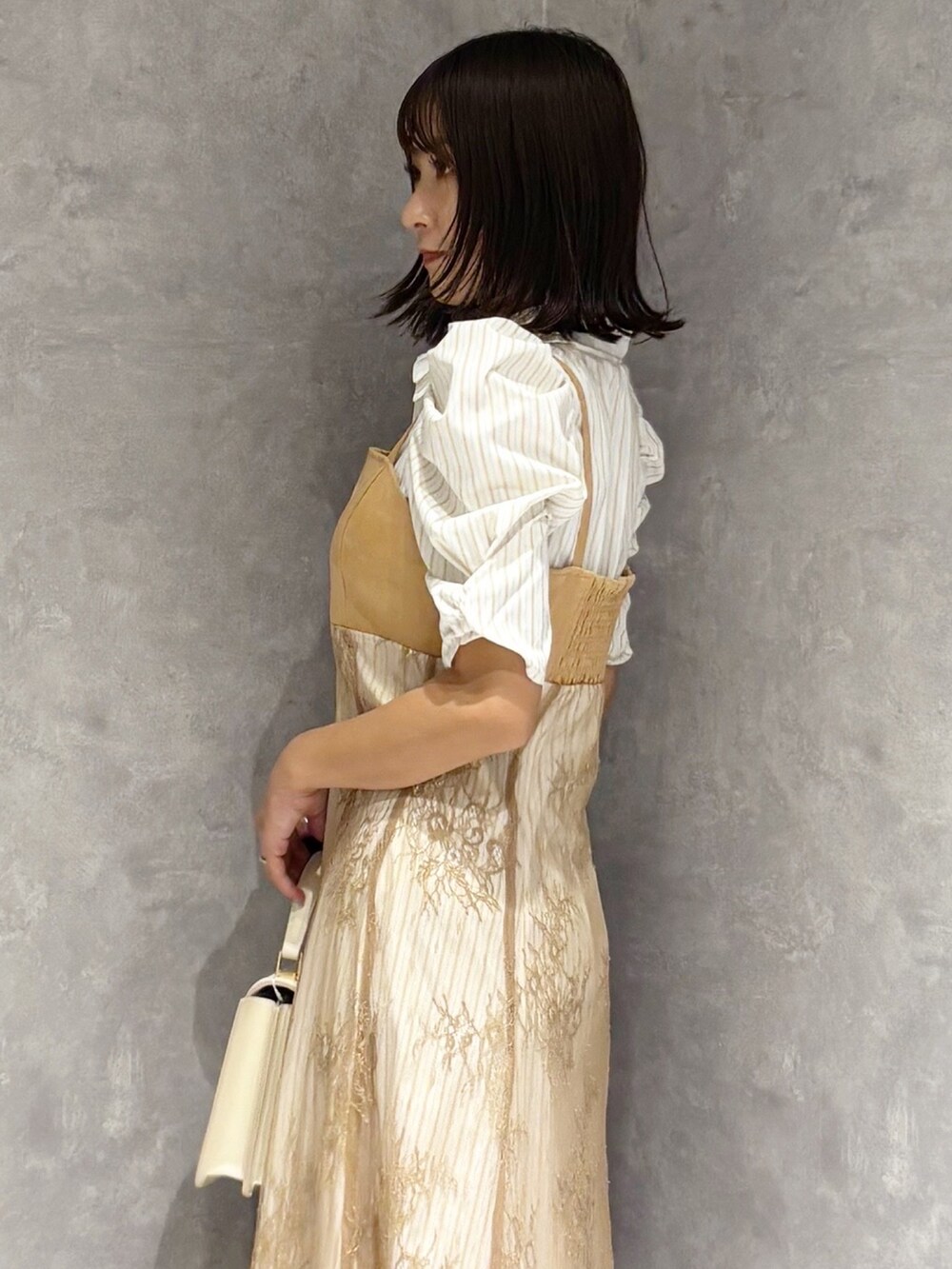 ベージュ系のワンピース、シルバー系のパンプス、ホワイト系のハンドバッグを着用したレディースの夏コーディネートの4枚目の写真