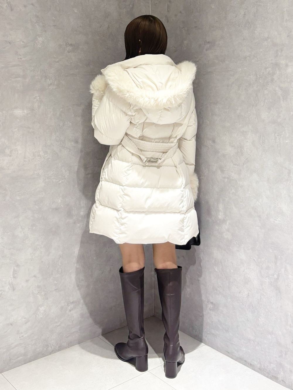 グレー系のスカート、ホワイト系のニット/セーター、ブラック系のハンドバッグを着用したレディースの冬コーディネートの3枚目の写真