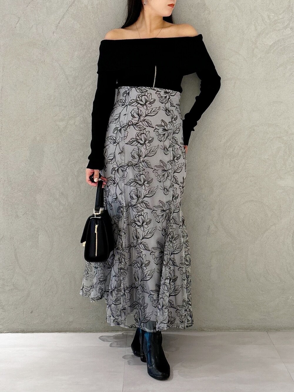 グレー系のスカート、ブラック系のブーツ、ブラック系のショルダーバッグを着用したレディースの秋コーディネートの9枚目の写真