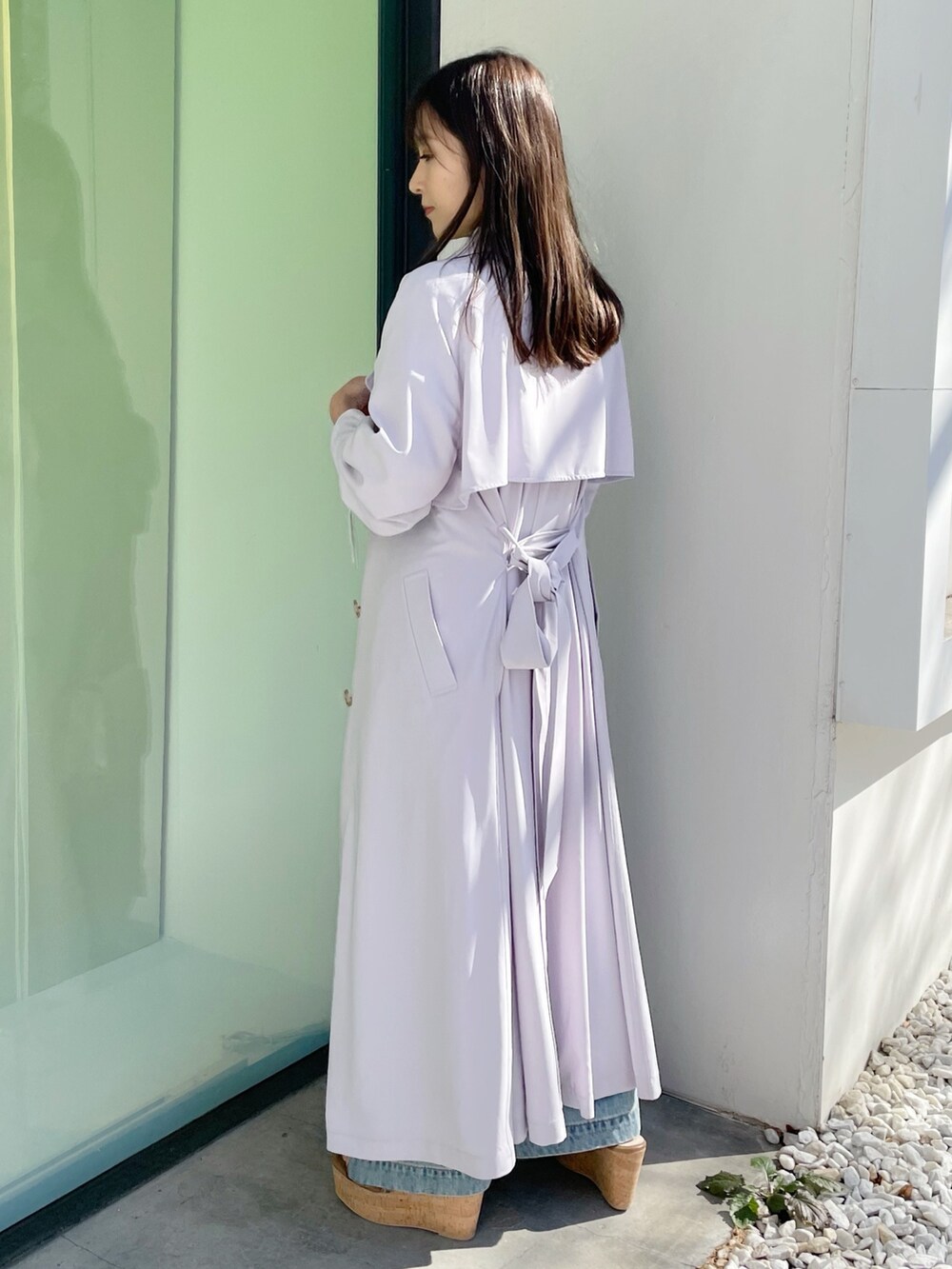 シルバー系のハンドバッグ、ブラック系のサンダル、ブルー系のデニムパンツを着用したレディースの春コーディネートの3枚目の写真