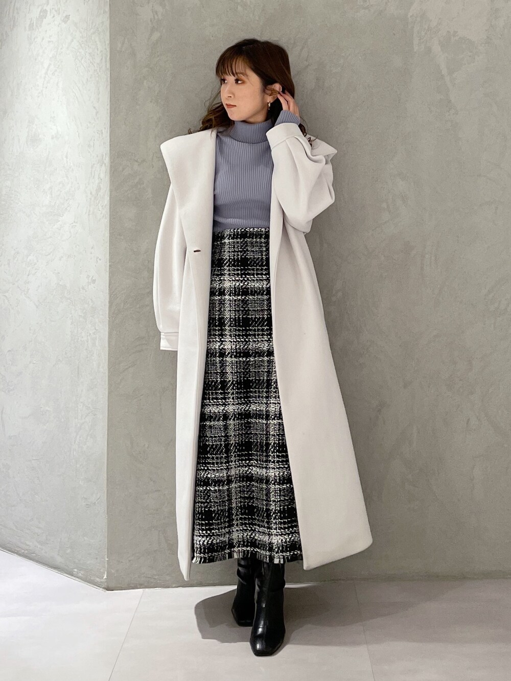 ブルー系のニット/セーター、ブラック系のスカート、ホワイト系のチェスターコートを着用したレディースの冬コーディネートの8枚目の写真