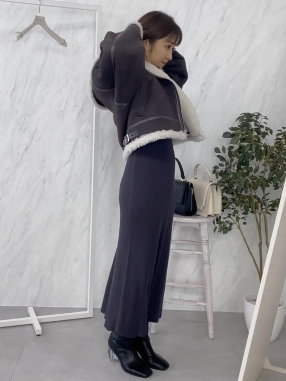 グレー系のワンピース、ブラック系のムートンコートを着用したレディースの秋コーディネートの2枚目の写真