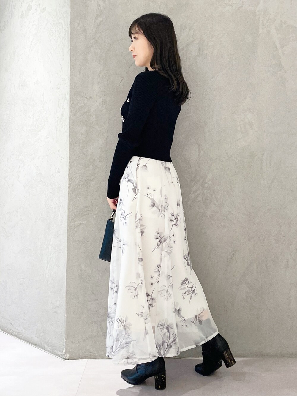 ブラック系のハンドバッグ、ブラック系のブーツ、ホワイト系のスカートを着用したレディースの冬コーディネートの2枚目の写真