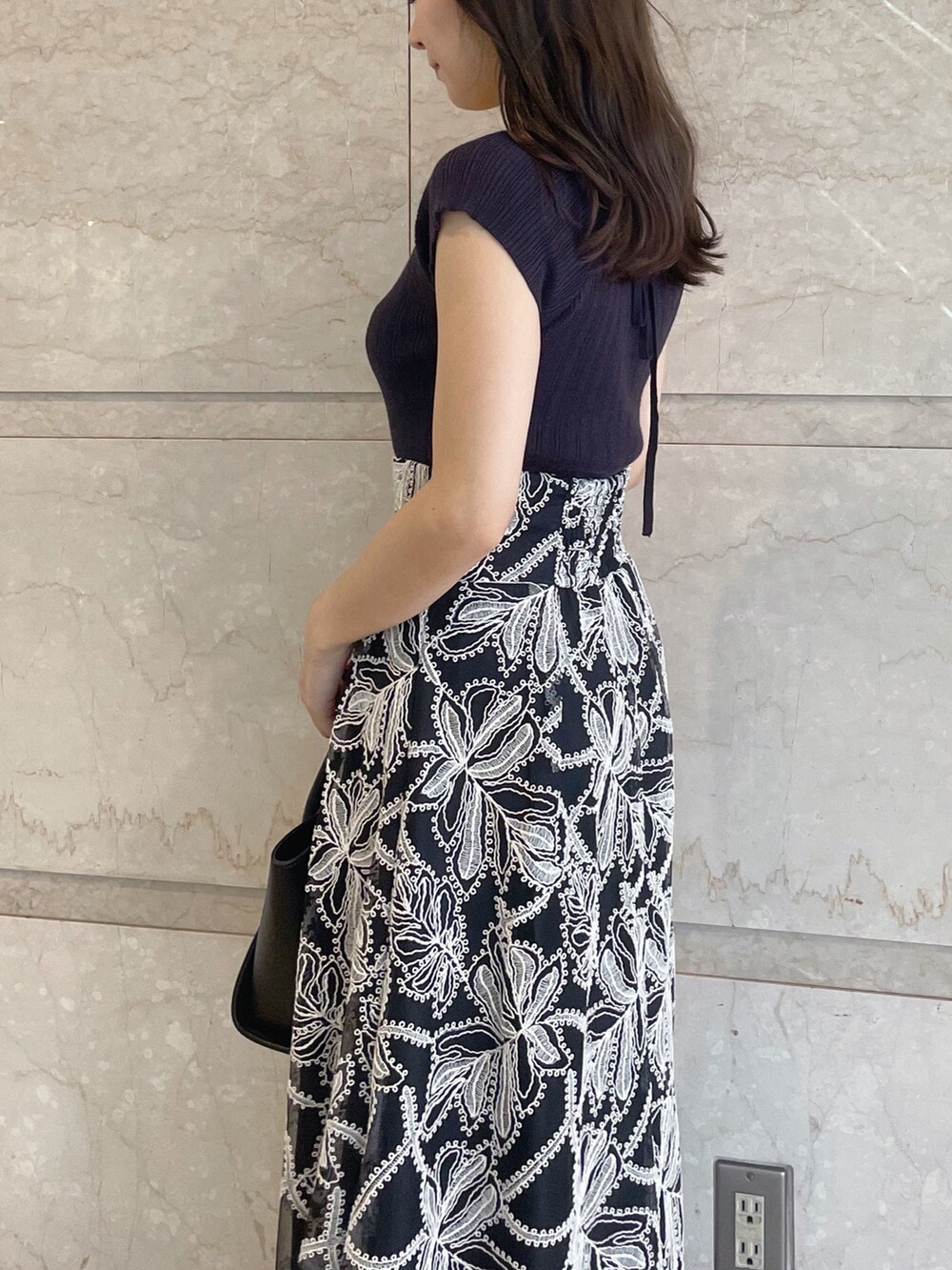 ブラック系のスカート、ブラック系のサンダル、ブラック系のトートバッグを着用したレディースの夏コーディネートの3枚目の写真