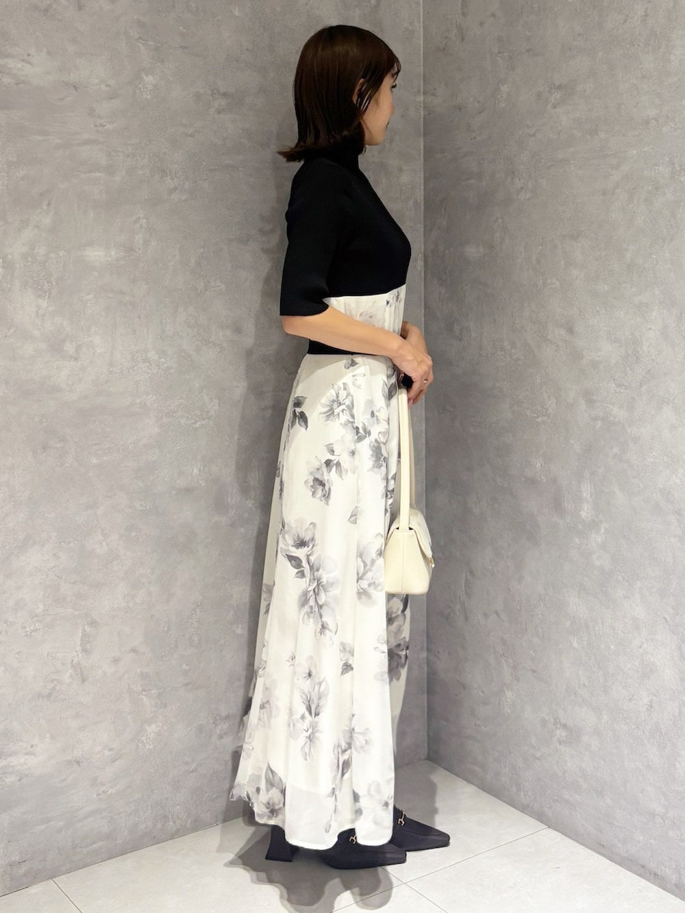 ブラック系のワンピース、ブラウン系のパンプス、ホワイト系のハンドバッグを着用したレディースの春コーディネートの4枚目の写真