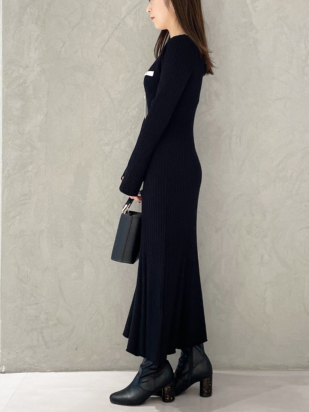 ブラック系のハンドバッグ、ブラック系のブーツ、ブラック系のワンピースを着用したレディースの冬コーディネートの5枚目の写真