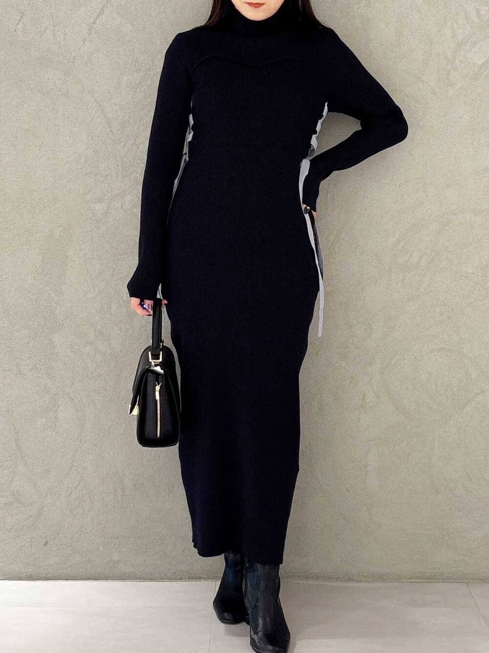 ブルー系のワンピース、ブラック系のブーツ、ブラック系のショルダーバッグを着用したレディースの冬コーディネートの6枚目の写真