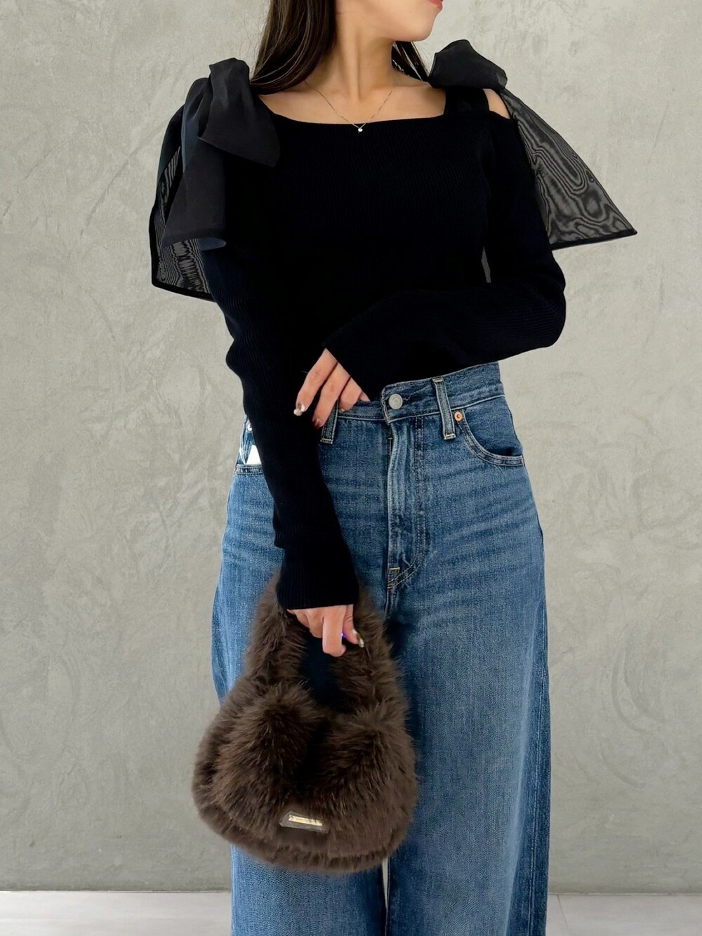 ブラウン系のハンドバッグ、シルバー系のパンプス、ブラック系のニット/セーターを着用したレディースの秋コーディネートの3枚目の写真