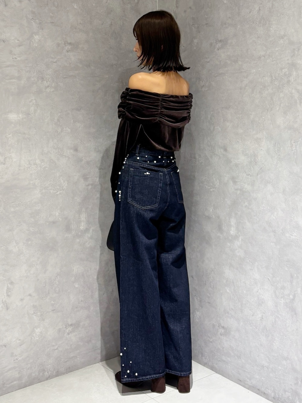 ブルー系のデニムパンツ、ブラウン系のTシャツ/カットソー、ブラウン系のブーツを着用したレディースの秋コーディネートの4枚目の写真