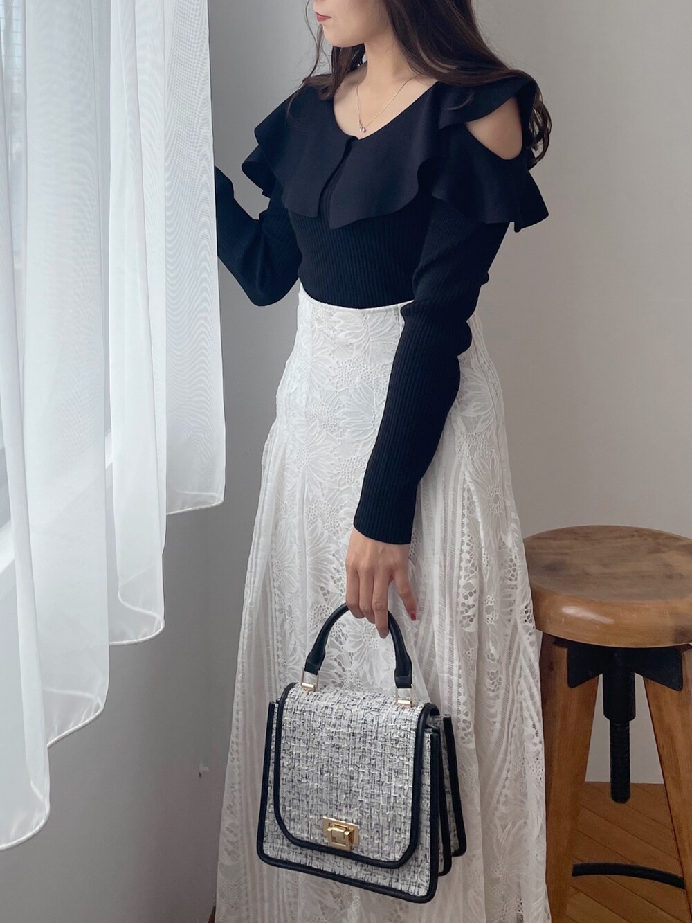 ホワイト系のスカート、ブラック系のショルダーバッグ、ブラウン系のブーツを着用したレディースの秋コーディネートの4枚目の写真