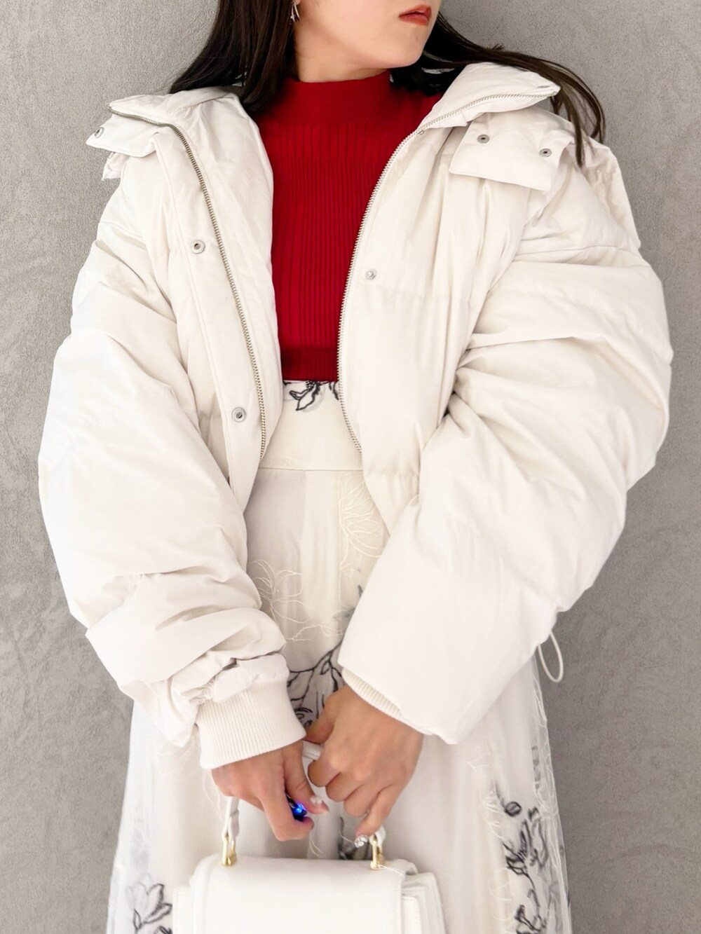 ホワイト系のスカート、ブラック系のブーツ、ホワイト系のハンドバッグを着用したレディースの冬コーディネートの2枚目の写真