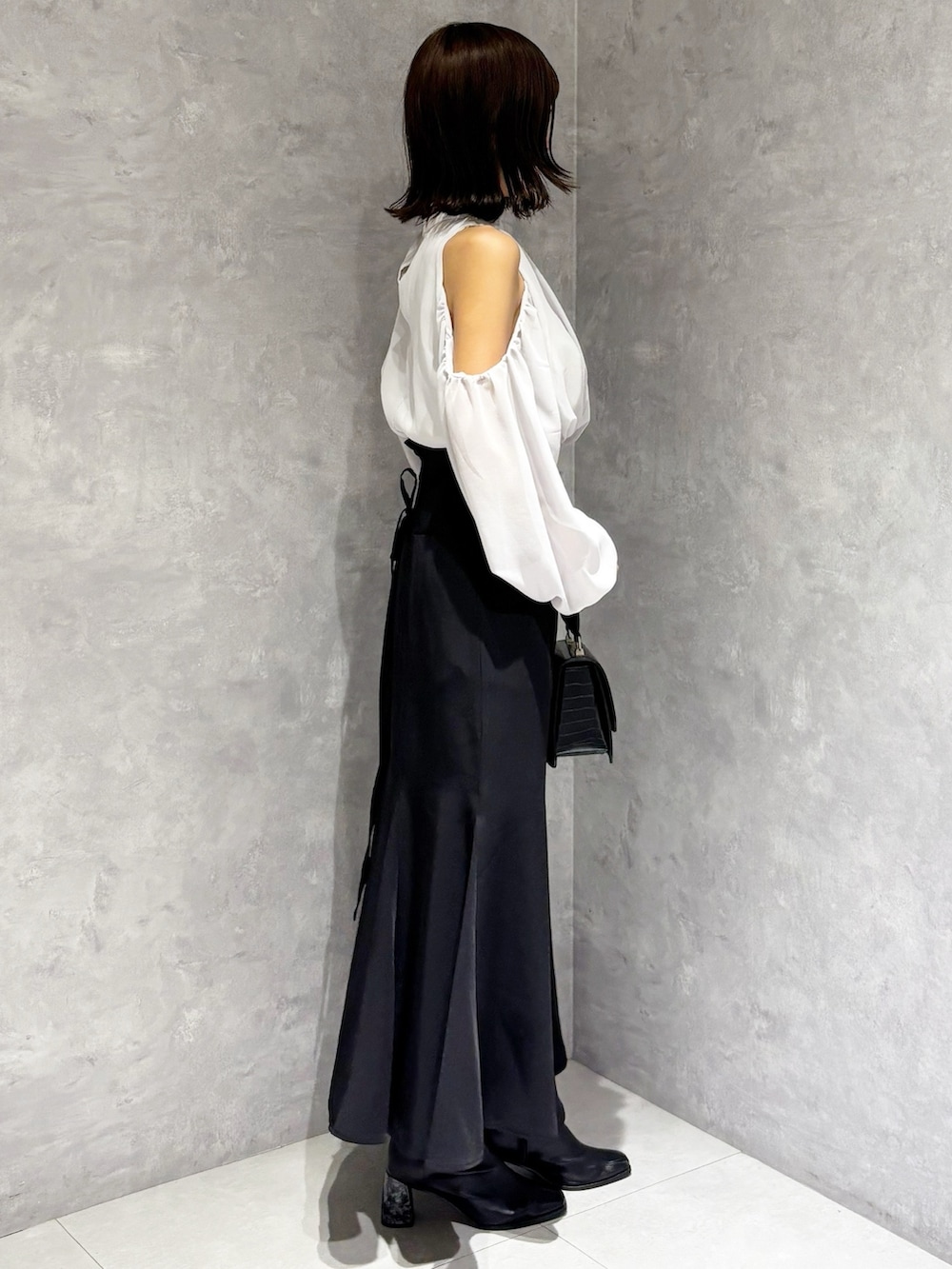 ブラック系のハンドバッグ、ブラック系のブーツ、ブラック系のスカートを着用したレディースの秋コーディネートの4枚目の写真