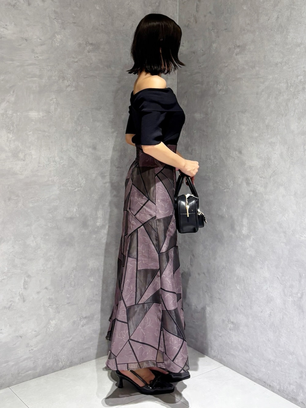 ブラウン系のスカート、ブラック系のハンドバッグ、ブラック系のニット/セーターを着用したレディースの夏コーディネートの4枚目の写真