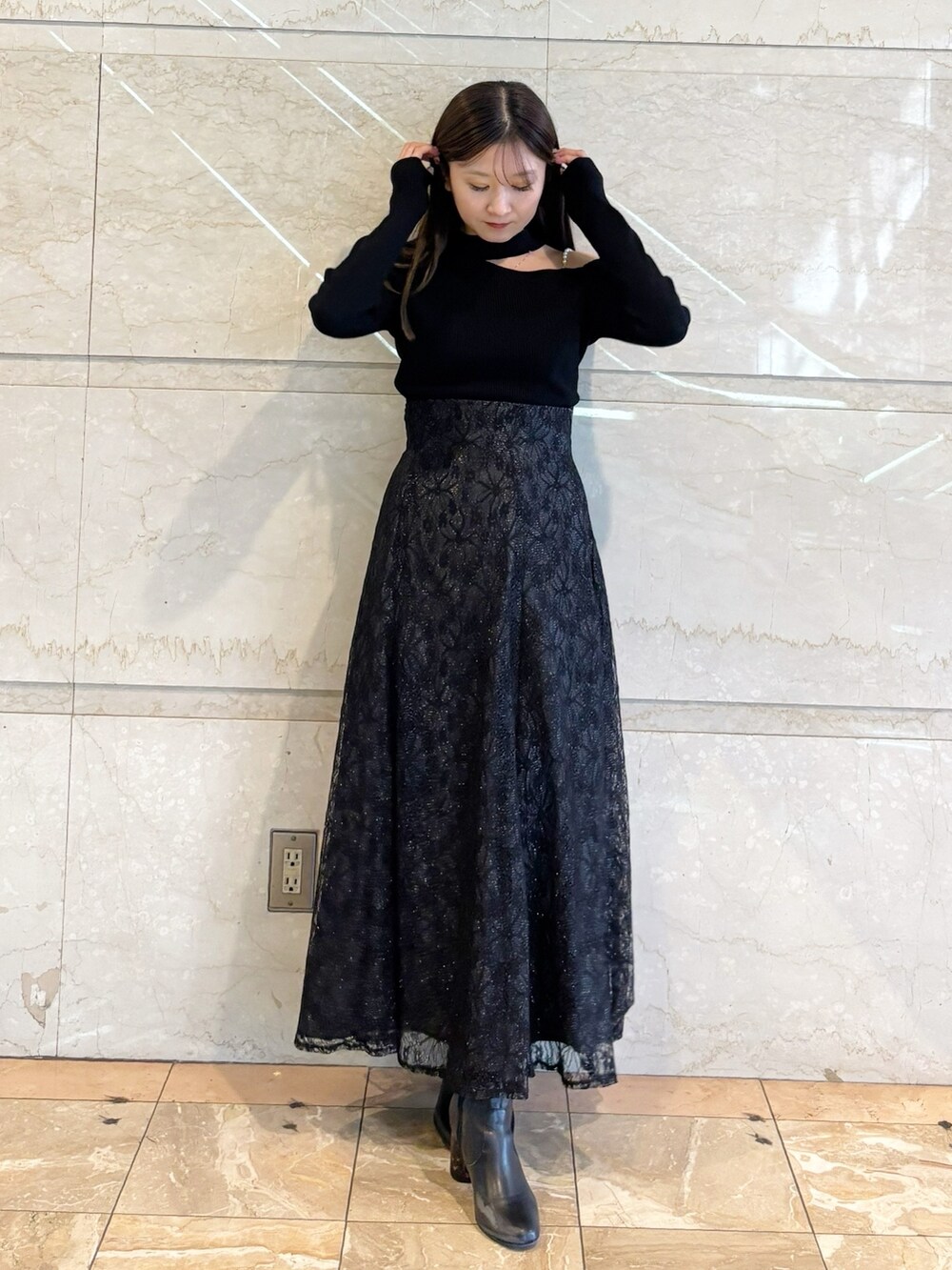 ブラック系のスカート、ブラック系のニット/セーター、ブラック系のブーツを着用したレディースの冬コーディネートの8枚目の写真