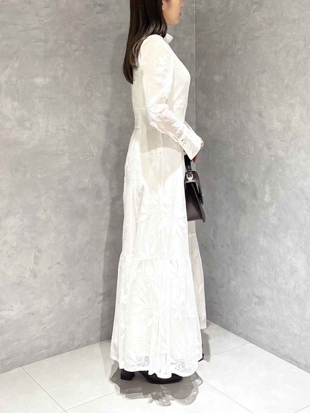 ホワイト系のワンピース、ブラウン系のハンドバッグ、ブラウン系のブーツを着用したレディースの冬コーディネートの2枚目の写真