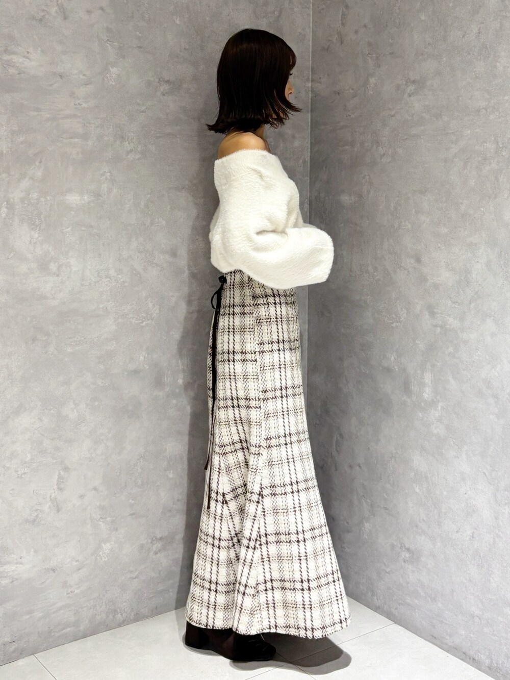 ホワイト系のスカート、ホワイト系のニット/セーター、ブラウン系のブーツを着用したレディースの秋コーディネートの4枚目の写真