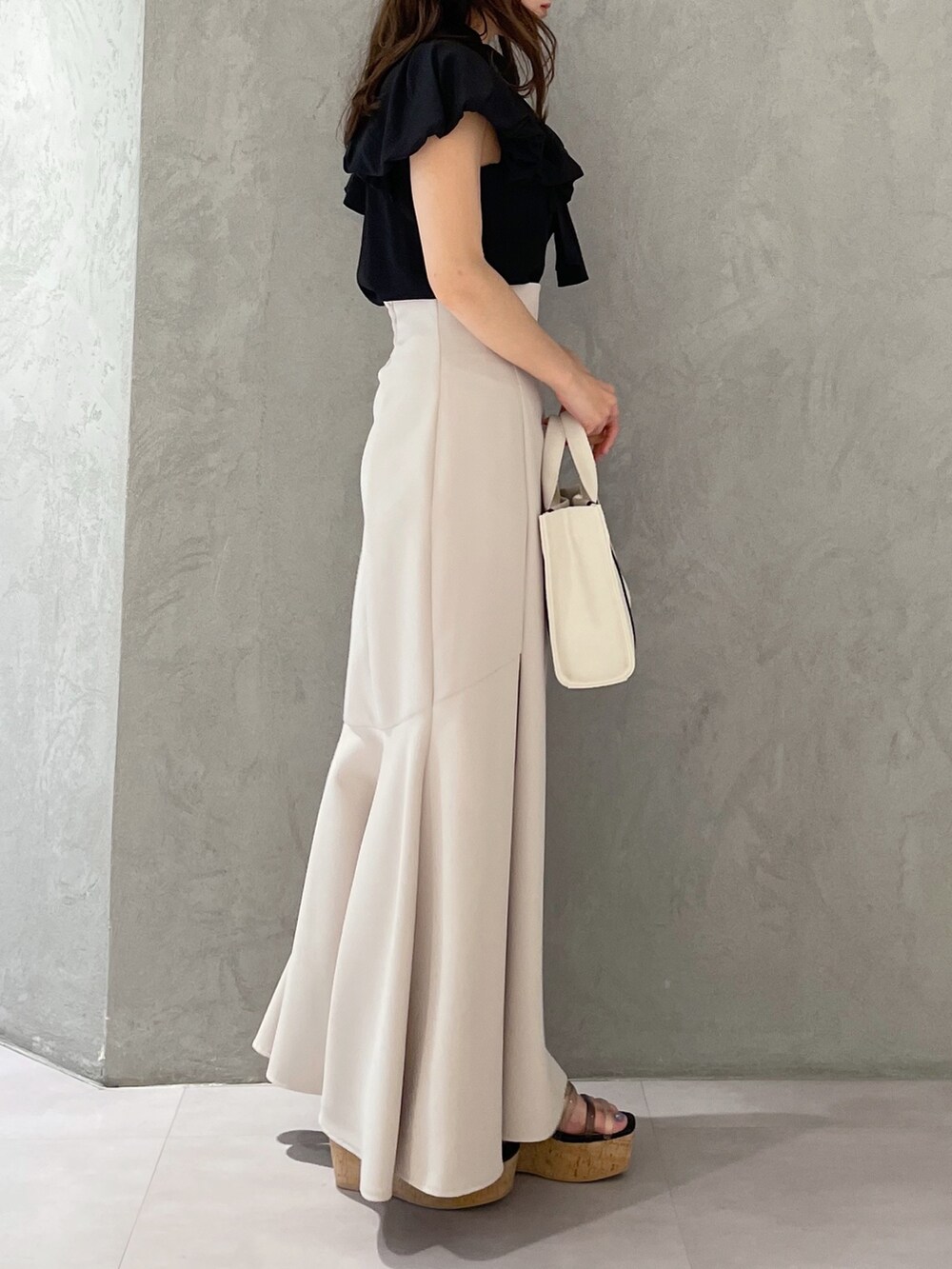 グレー系のハンドバッグ、ベージュ系のスカート、ブラック系のサンダルを着用したレディースの春コーディネートの6枚目の写真